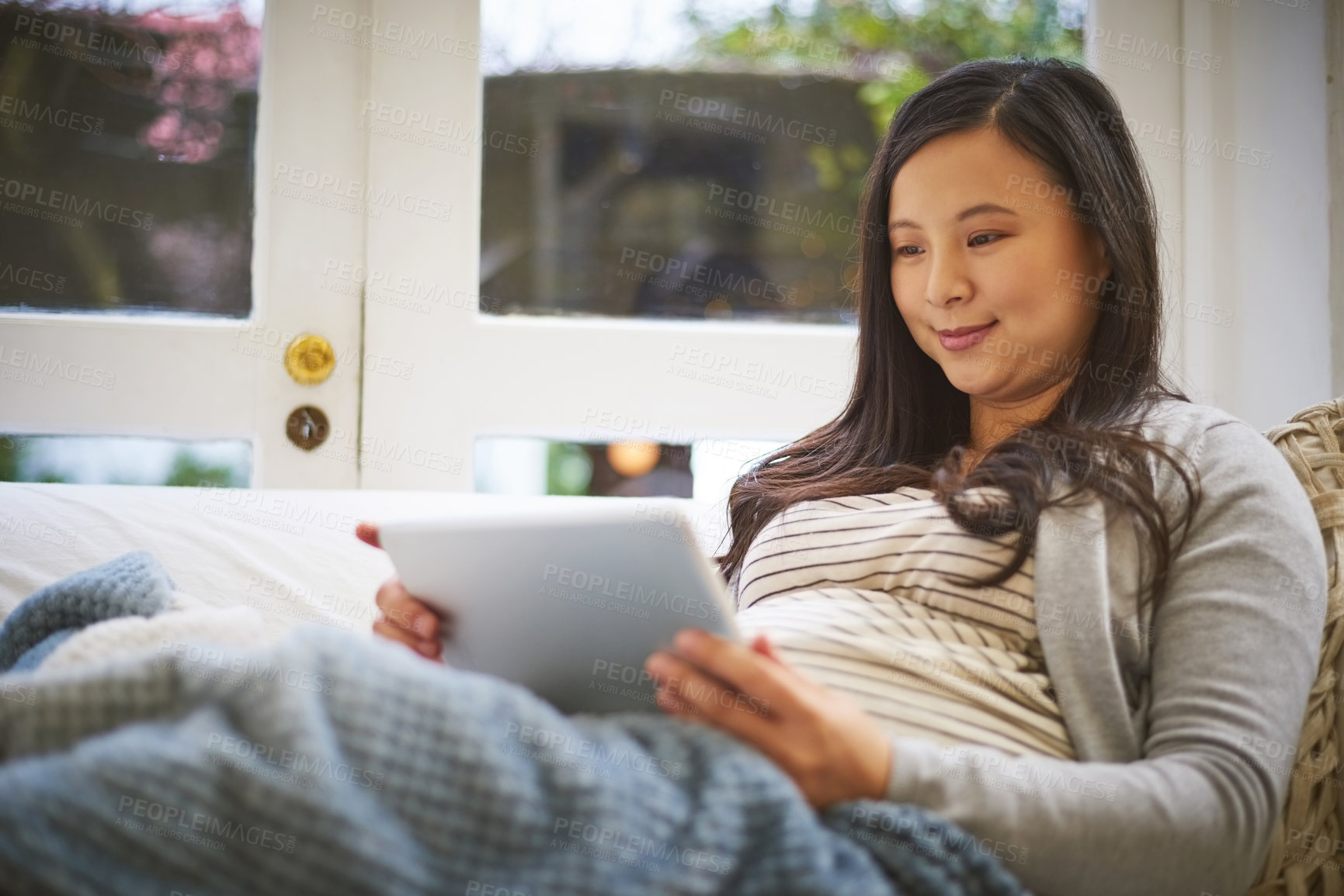 Buy stock photo Shot of a pregnant woman using a digital tablet at home