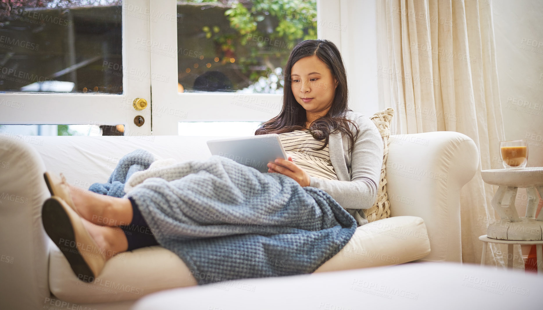 Buy stock photo Shot of a pregnant woman using a digital tablet at home