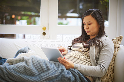 Buy stock photo Shot of a pregnant woman using a digital tablet at home