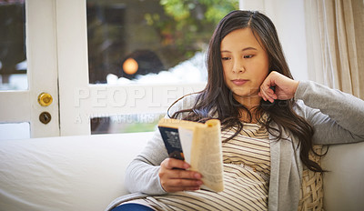 Buy stock photo Shot of a pregnant woman reading a book at home