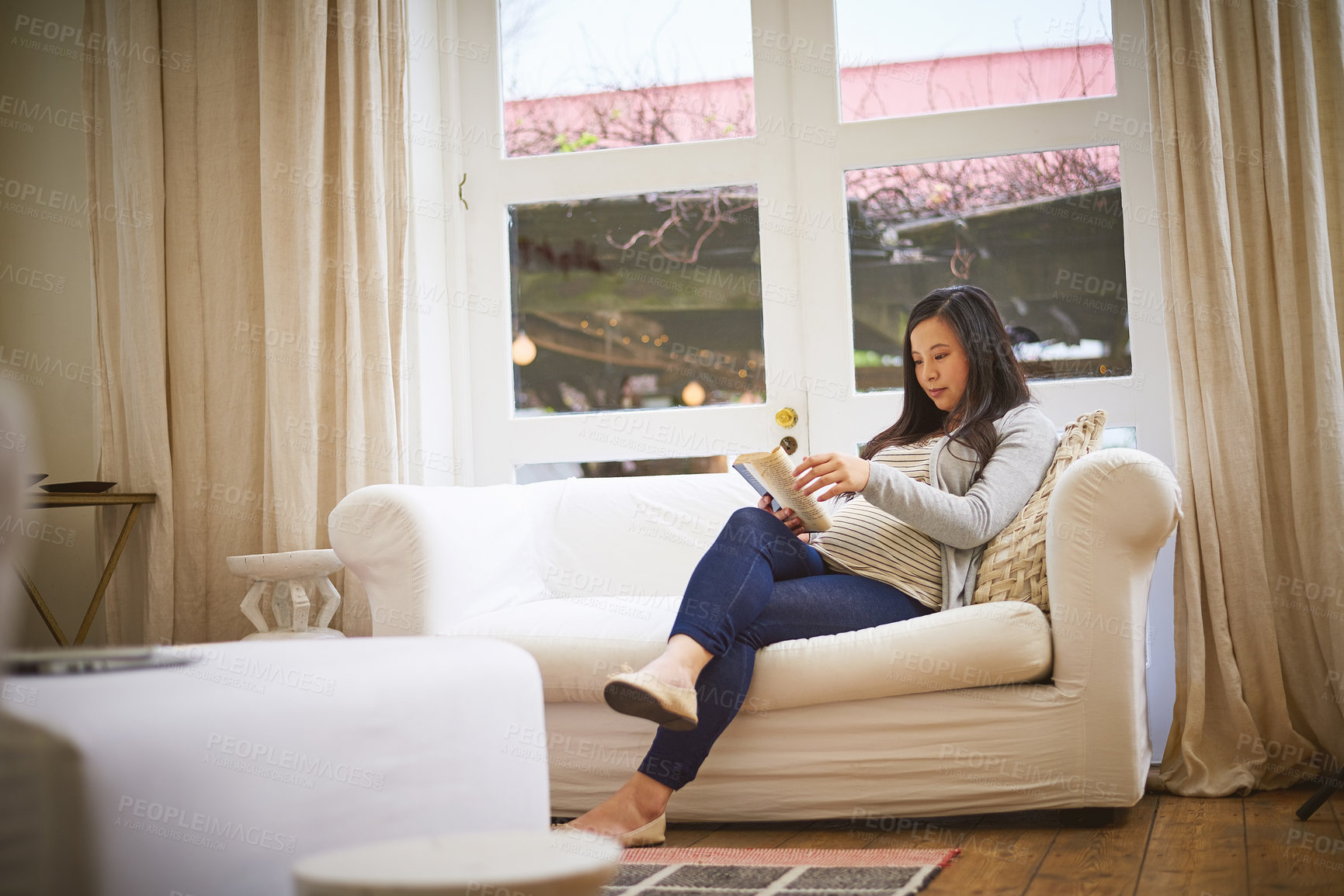 Buy stock photo Shot of a pregnant woman reading a book at home