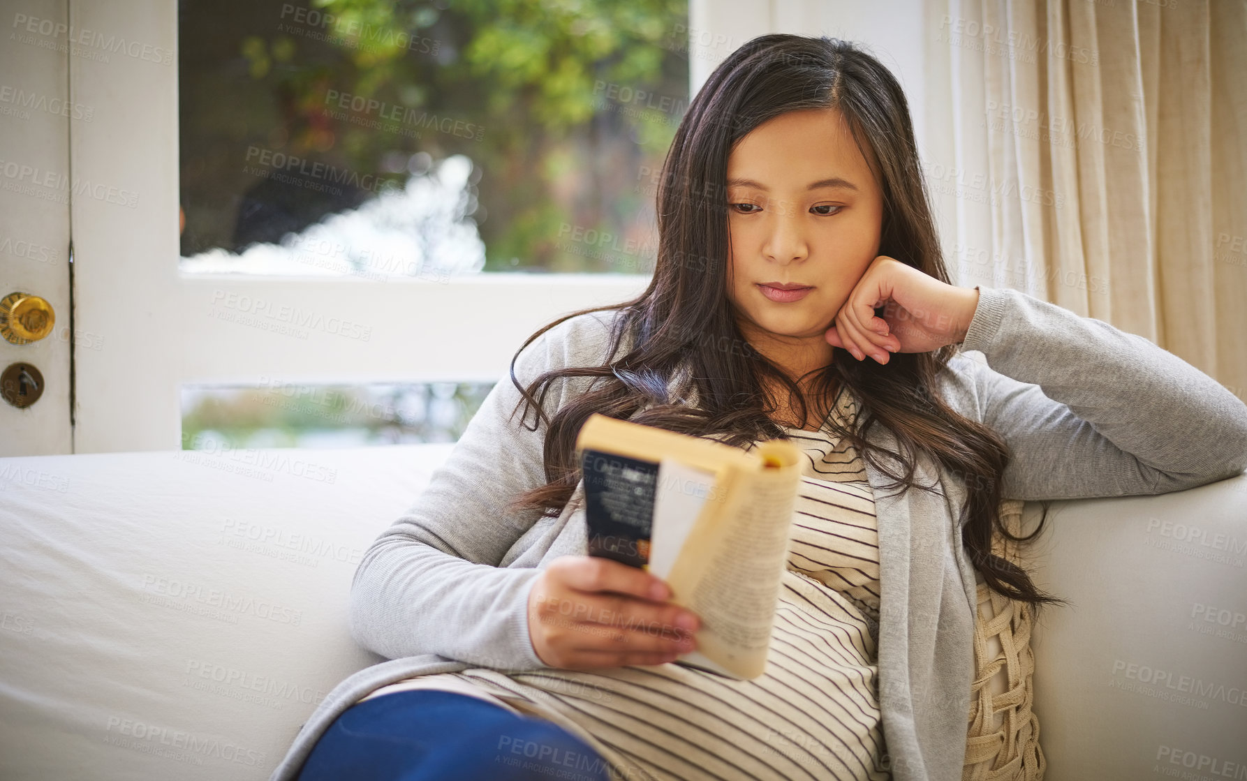 Buy stock photo Shot of a pregnant woman reading a book at home