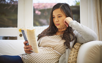 Buy stock photo Shot of a pregnant woman reading a book at home