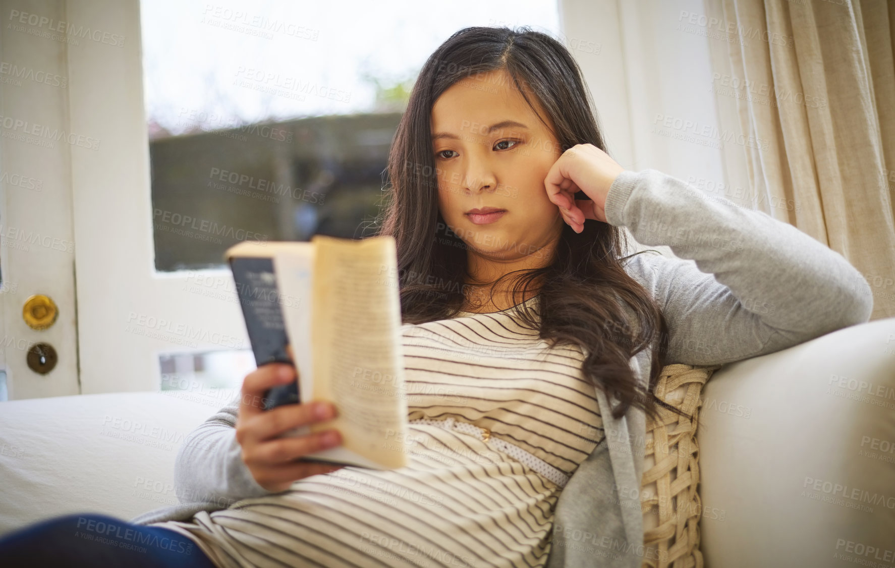 Buy stock photo Shot of a pregnant woman reading a book at home