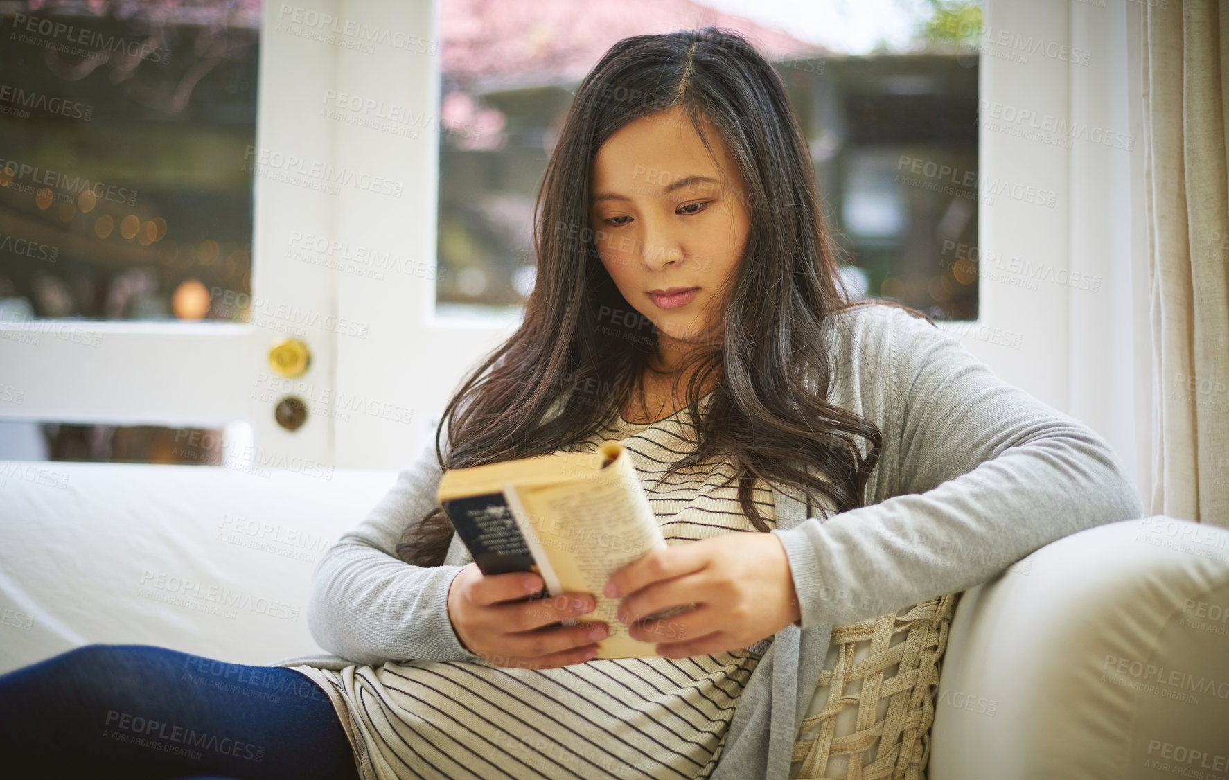 Buy stock photo Shot of a pregnant woman reading a book at home