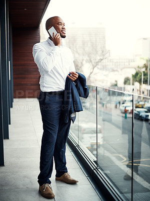 Buy stock photo Shot of a handsome young businessman talking on a cellphone outside his office