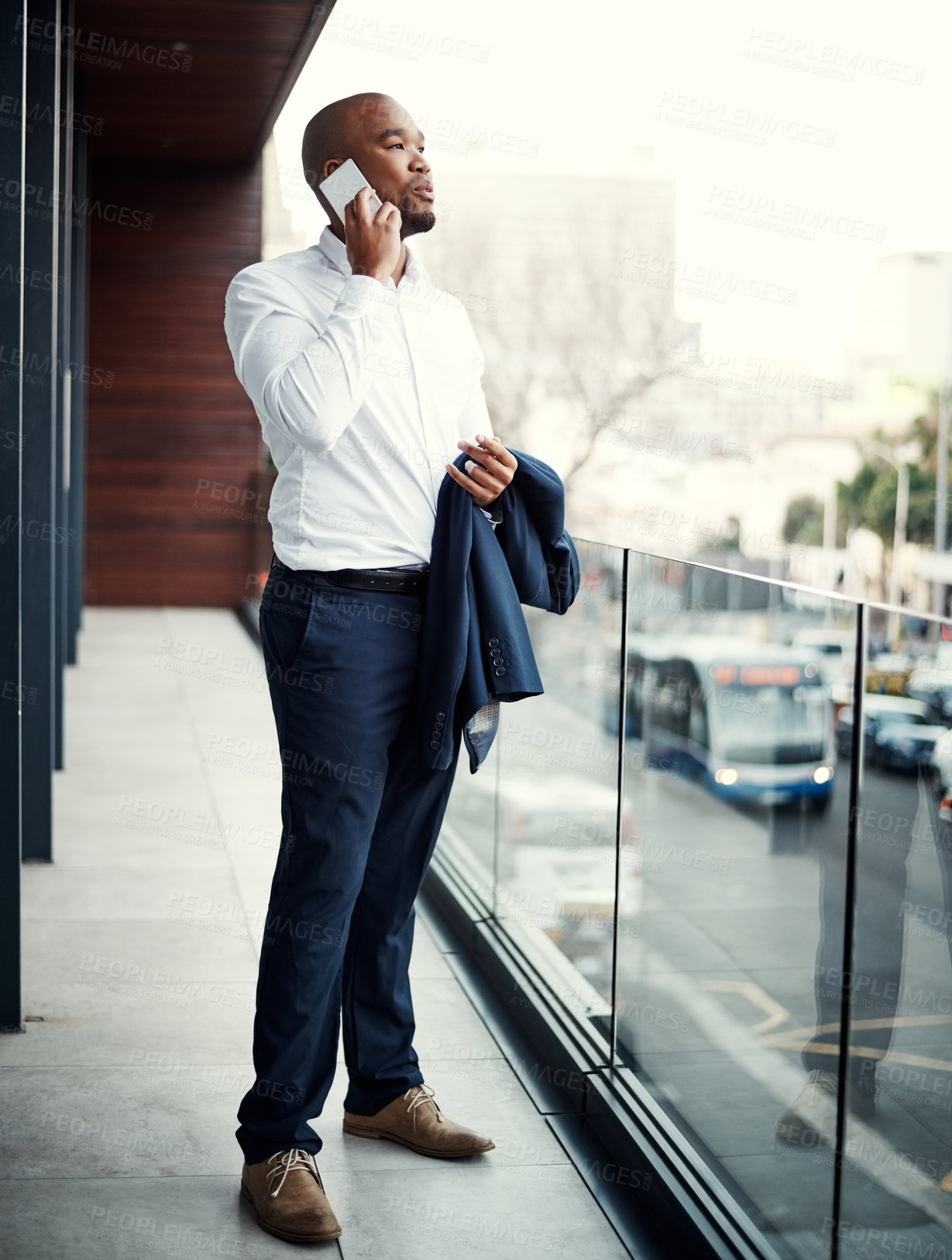 Buy stock photo Shot of a handsome young businessman talking on a cellphone outside his office