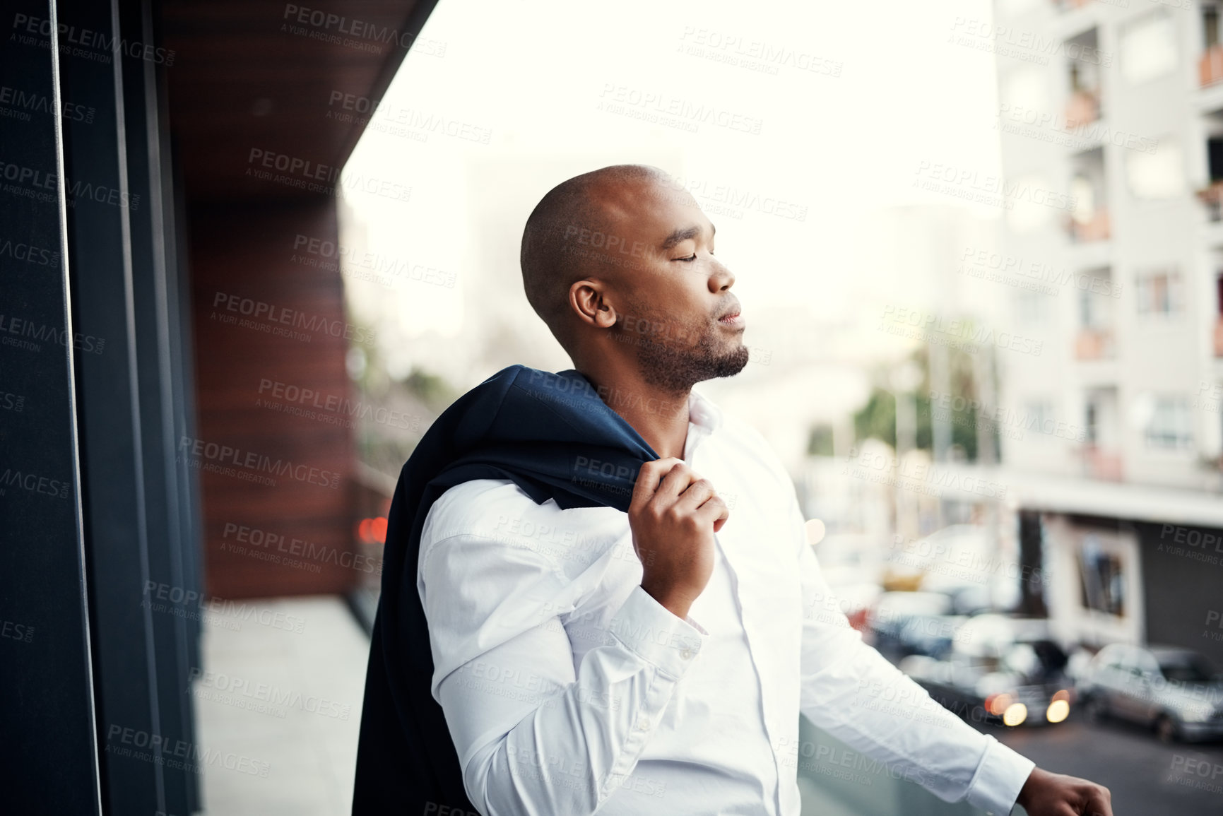 Buy stock photo Shot of a handsome young businessman standing outside on his office balcony