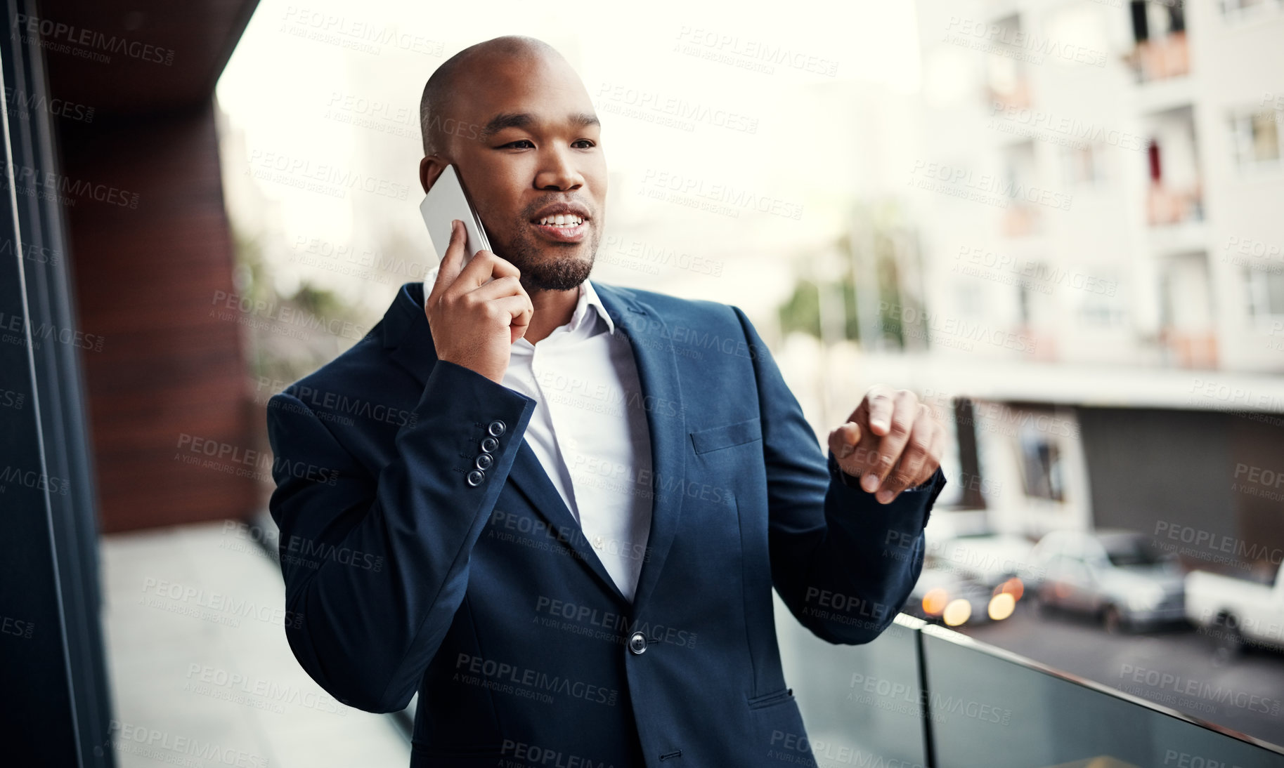 Buy stock photo Shot of a handsome young businessman talking on a cellphone outside his office