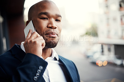 Buy stock photo Shot of a handsome young businessman talking on a cellphone outside his office