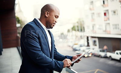 Buy stock photo Shot of a handsome young businessman using a digital tablet outside his office