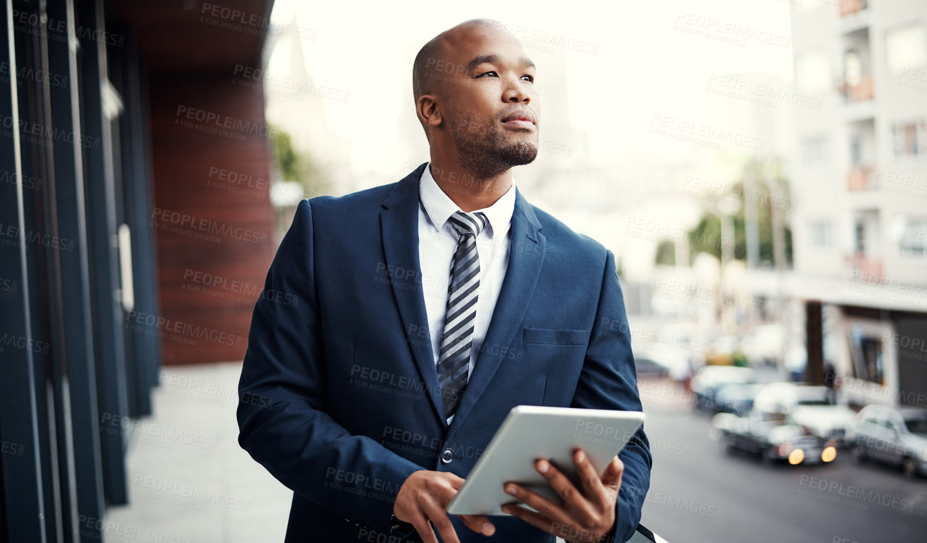 Buy stock photo Shot of a handsome young businessman using a digital tablet outside his office