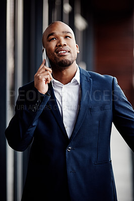 Buy stock photo Shot of a handsome young businessman talking on a cellphone outside his office