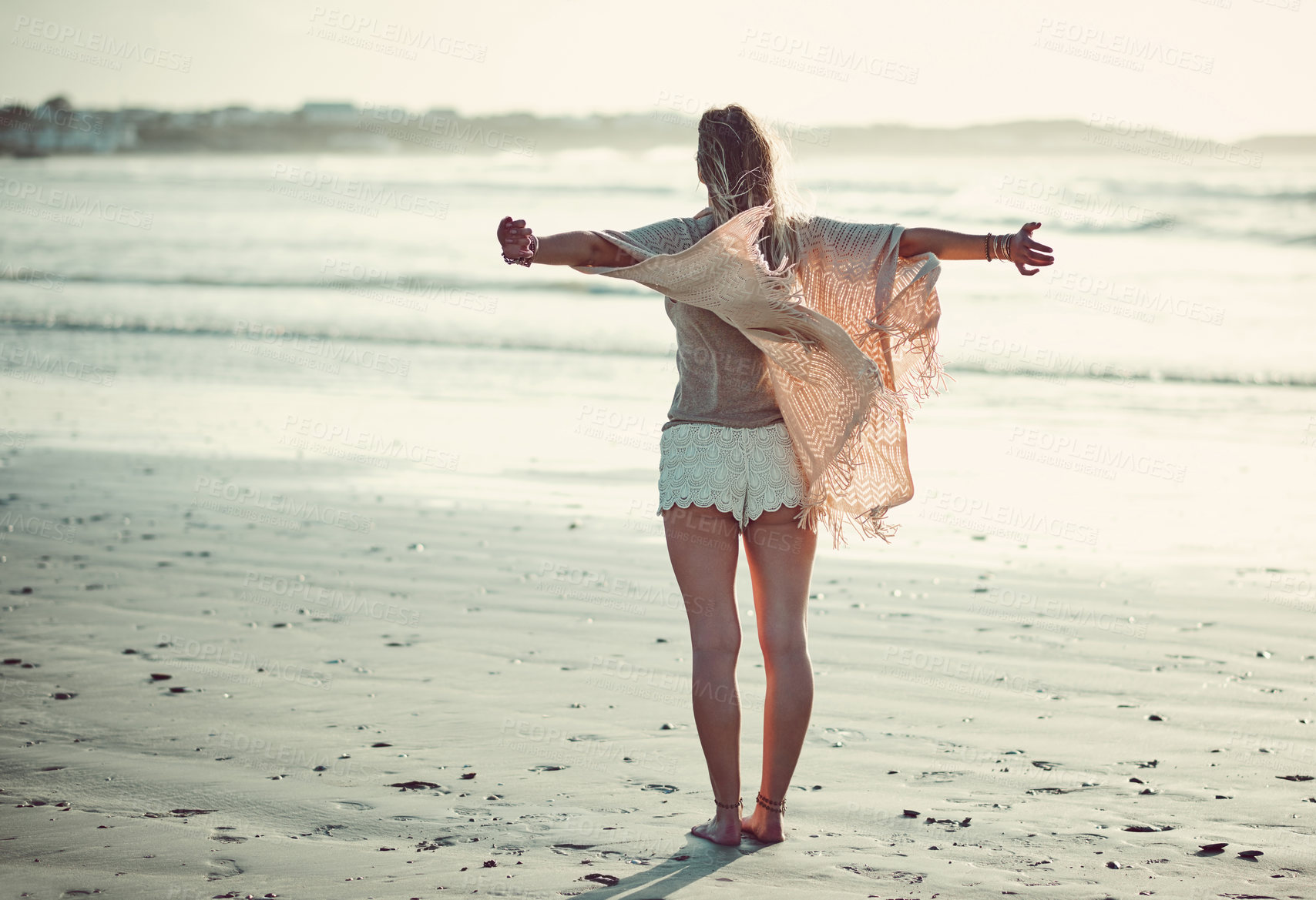 Buy stock photo Rearview shot of an unrecognizable woman spending a day at the beach