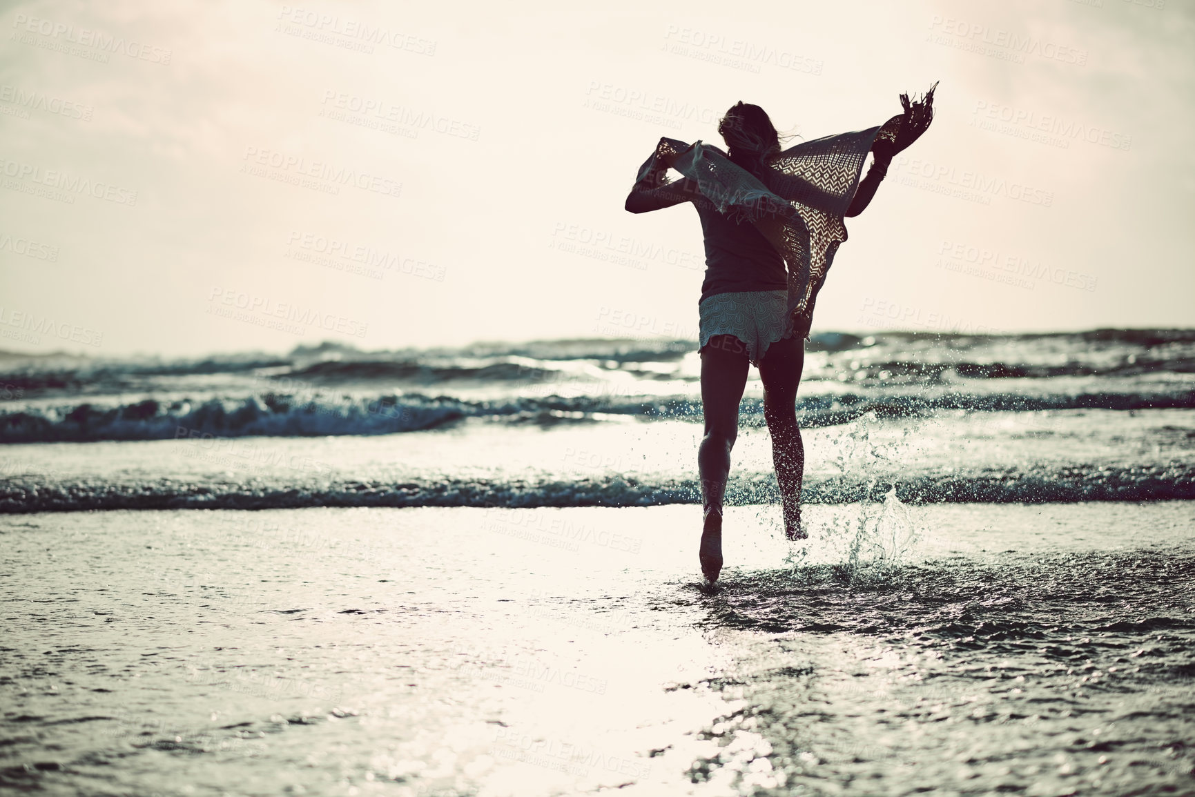 Buy stock photo Rearview shot of an unrecognizable woman spending a day at the beach