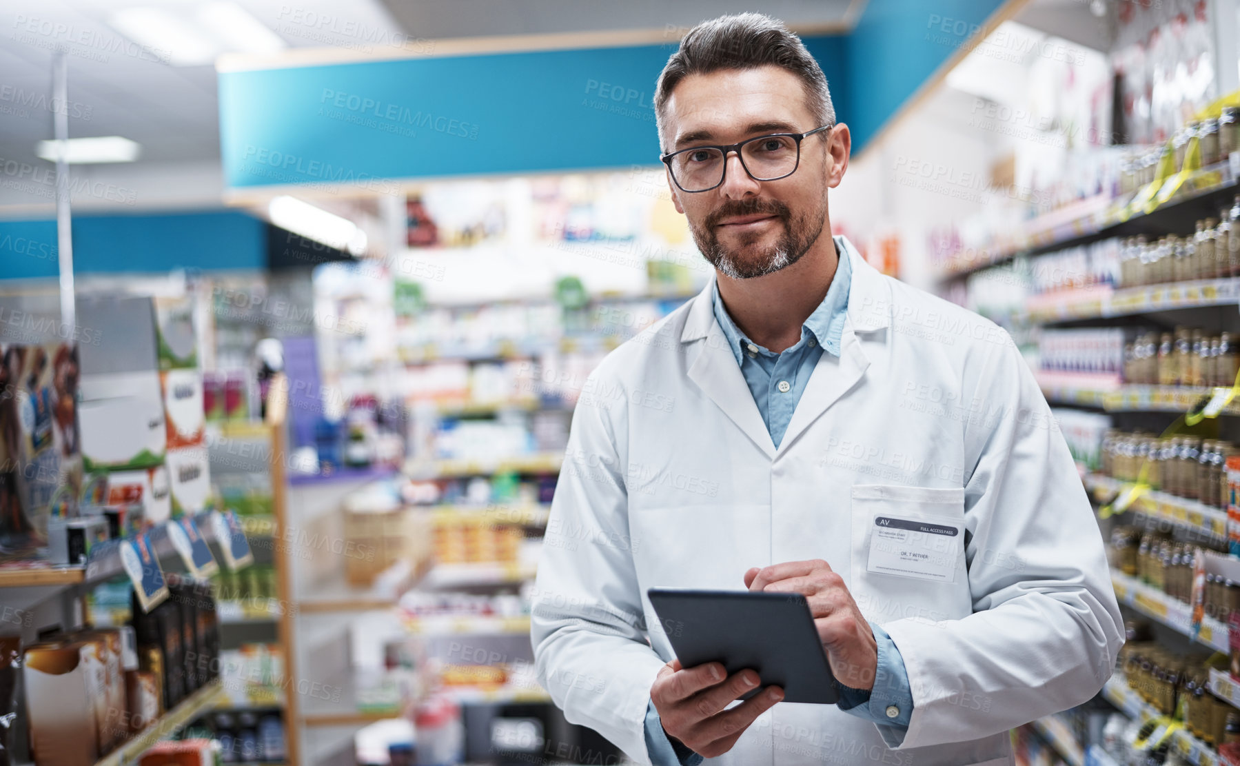 Buy stock photo Portrait of a handsome mature pharmacist using a digital tablet in a pharmacy