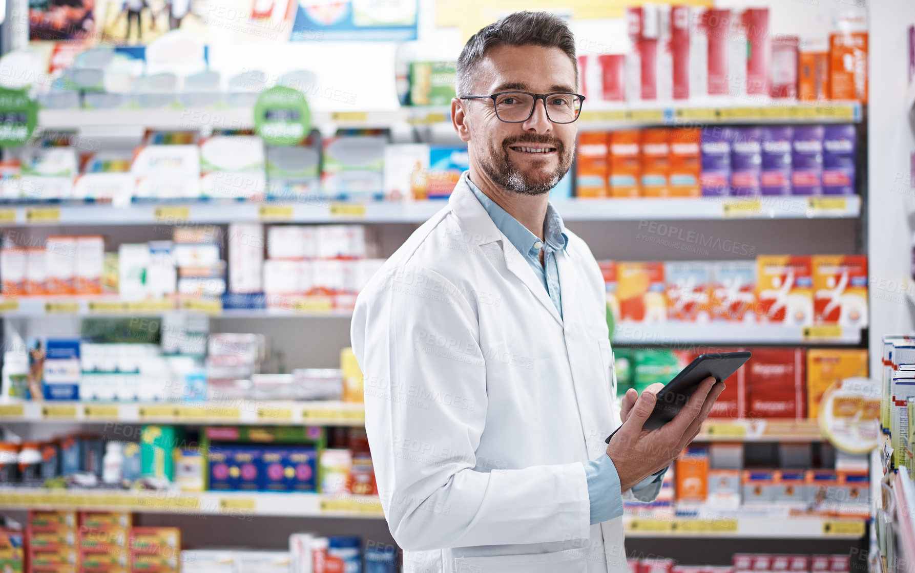 Buy stock photo Portrait of a handsome mature pharmacist using a digital tablet in a pharmacy