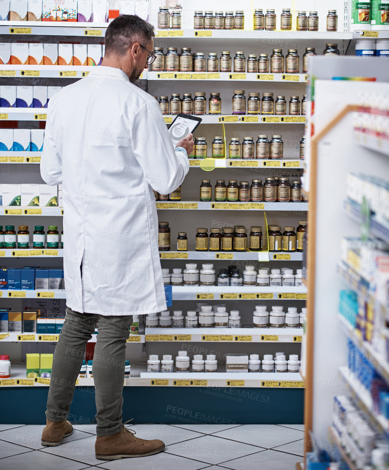 Buy stock photo Shot of a mature pharmacist using a digital tablet in a pharmacy