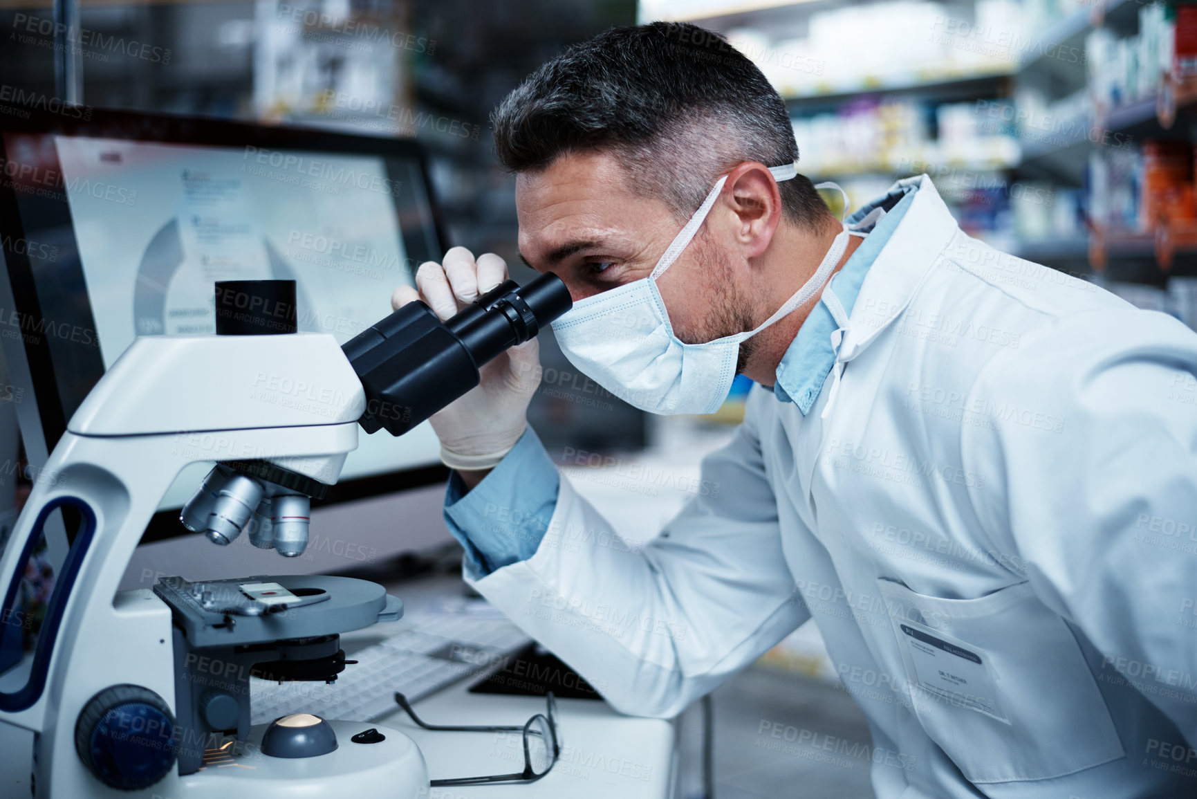 Buy stock photo Shot of a mature man using a microscope while conducting pharmaceutical research