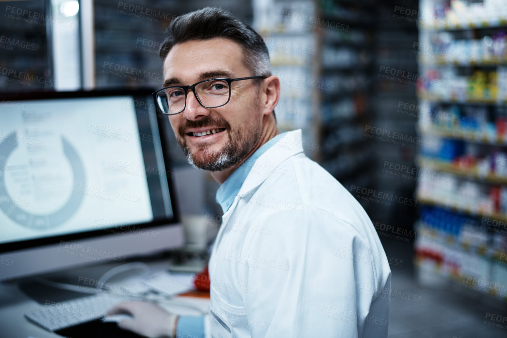 Buy stock photo Shot of a mature man using a computer while working in a pharmacy