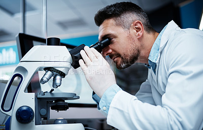 Buy stock photo Shot of a mature man using a microscope while conducting pharmaceutical research