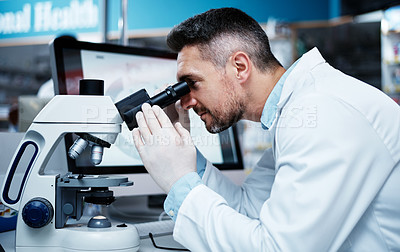 Buy stock photo Shot of a mature man using a microscope while conducting pharmaceutical research