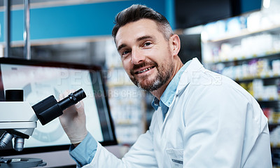 Buy stock photo Shot of a mature man using a microscope while conducting pharmaceutical research