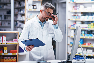 Buy stock photo Shot of a mature pharmacist writing on a clipboard in a pharmacy