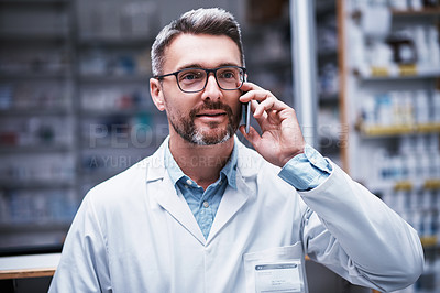 Buy stock photo Shot of a mature pharmacist talking on a cellphone in a pharmacy