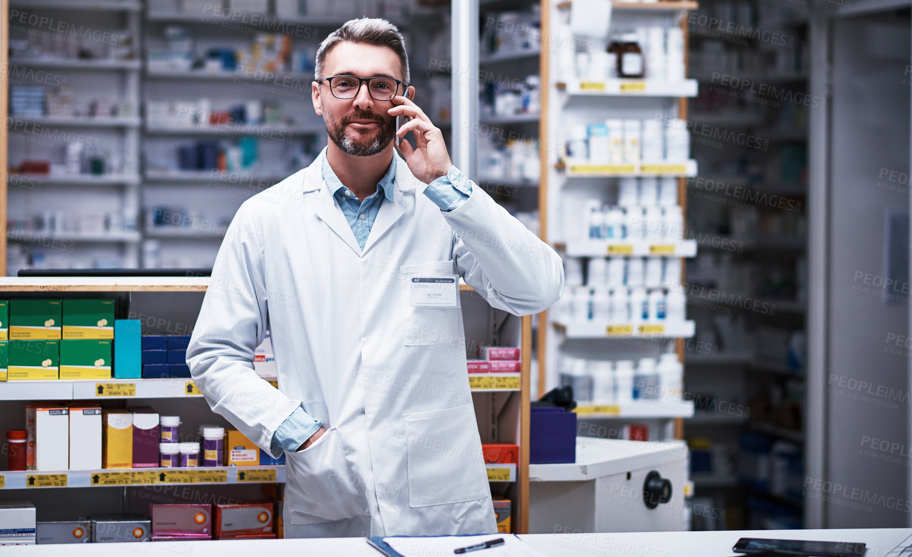 Buy stock photo Portrait of a mature pharmacist talking on a cellphone in a pharmacy