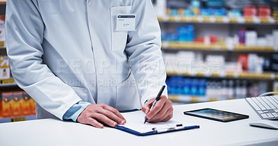 Buy stock photo Closeup shot of an unrecognizable pharmacist writing on a clipboard in a pharmacy