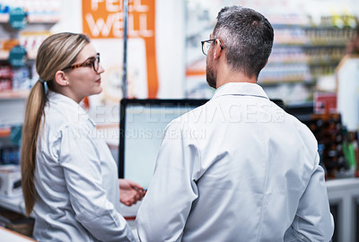 Buy stock photo Rearview shot of two pharmacists working in a pharmacy