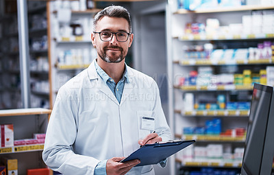 Buy stock photo Portrait of a mature pharmacist writing on a clipboard in a pharmacy