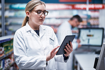 Buy stock photo Shot of a young pharmacist using a digital tablet in a pharmacy