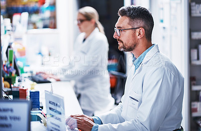 Buy stock photo Shot of a mature pharmacist working on a computer in a pharmacy