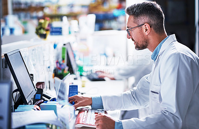 Buy stock photo Shot of a mature pharmacist working on a computer in a pharmacy