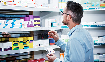 Buy stock photo Shot of a mature man looking at products in a pharmacy