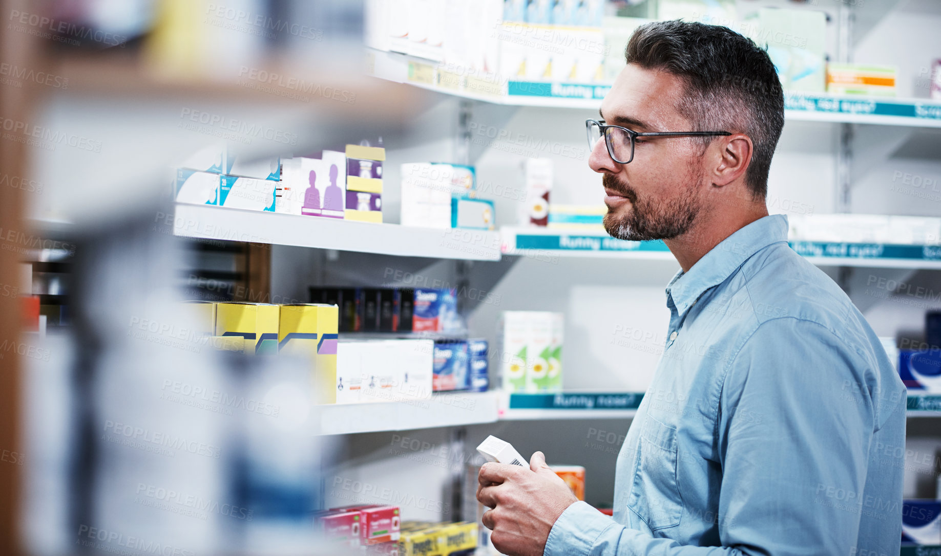 Buy stock photo Shot of a mature man looking at products in a pharmacy