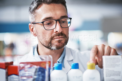 Buy stock photo Shot of a mature pharmacist checking products in a pharmacy