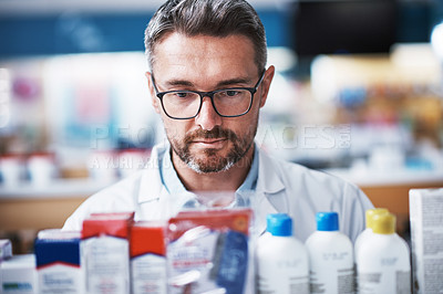 Buy stock photo Shot of a mature pharmacist checking products in a pharmacy