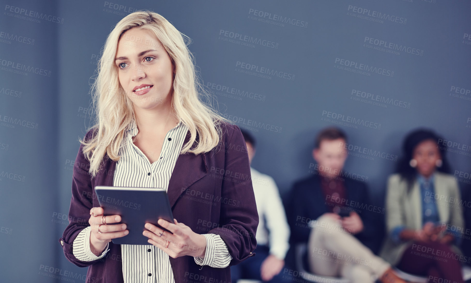 Buy stock photo Cropped shot of an attractive young businesswoman using a tablet with her colleagues in the background