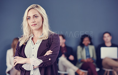 Buy stock photo Cropped shot of an attractive young businesswoman standing with her arms folded with her colleagues in the background