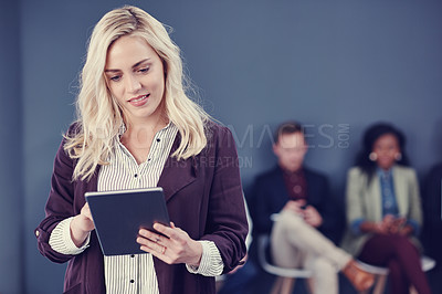 Buy stock photo Cropped shot of an attractive young businesswoman using a tablet with her colleagues in the background