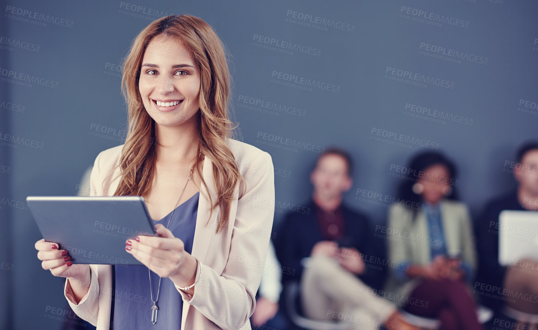 Buy stock photo Cropped portrait of an attractive young businesswoman using a tablet with her colleagues in the background