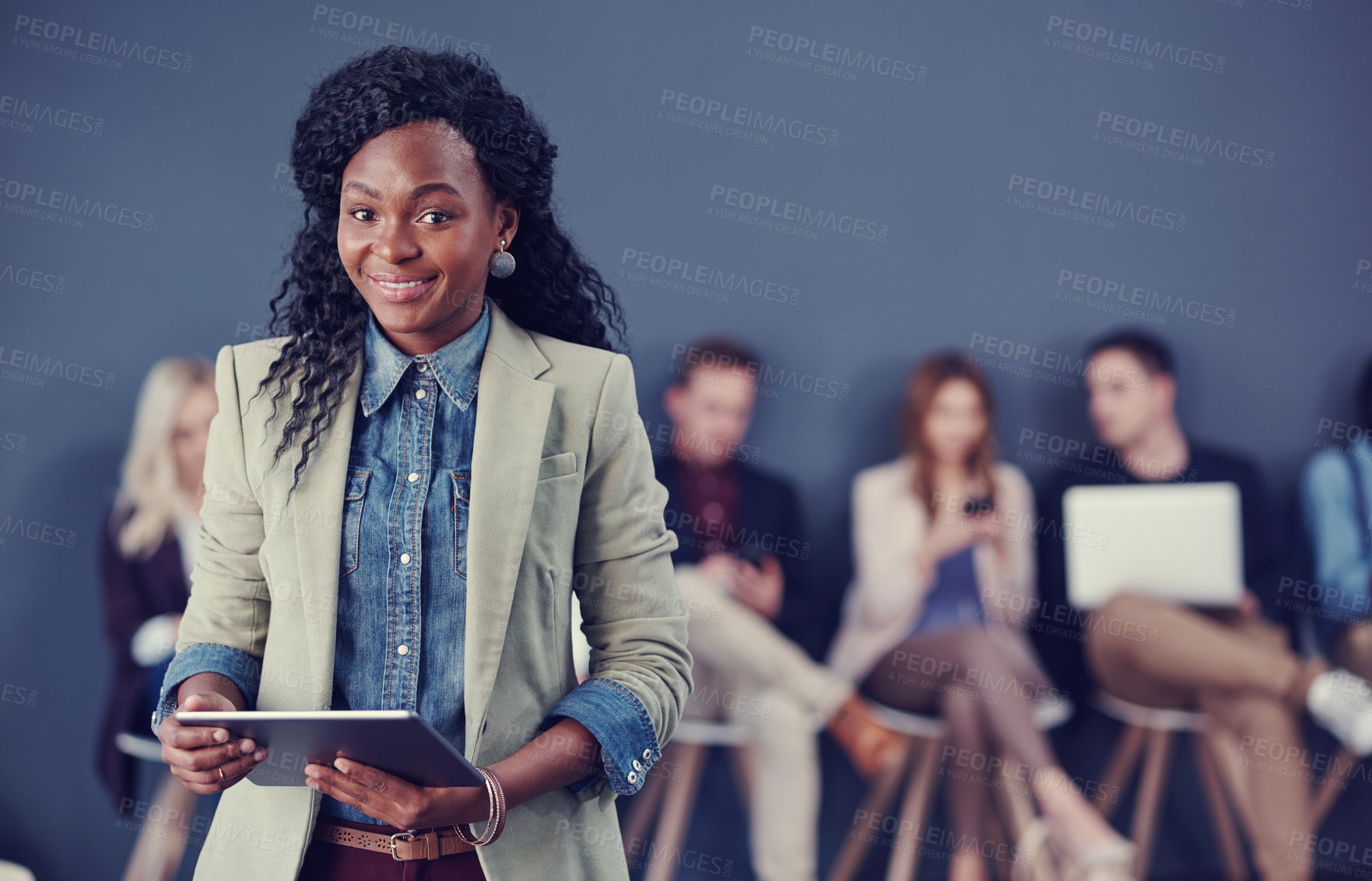 Buy stock photo Cropped portrait of an attractive young businesswoman using a tablet with her colleagues in the background