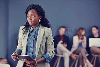 Buy stock photo Cropped shot of an attractive young businesswoman using a tablet with her colleagues in the background