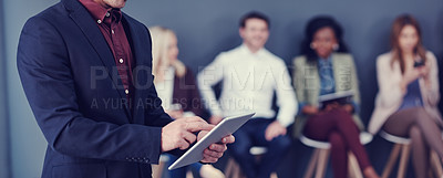 Buy stock photo Cropped shot of an unrecognizable businessman using a tablet with his colleagues in the background