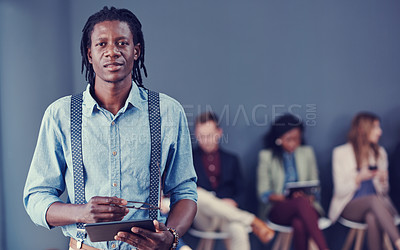 Buy stock photo Cropped portrait of a handsome young businessman using a tablet with his colleagues in the background