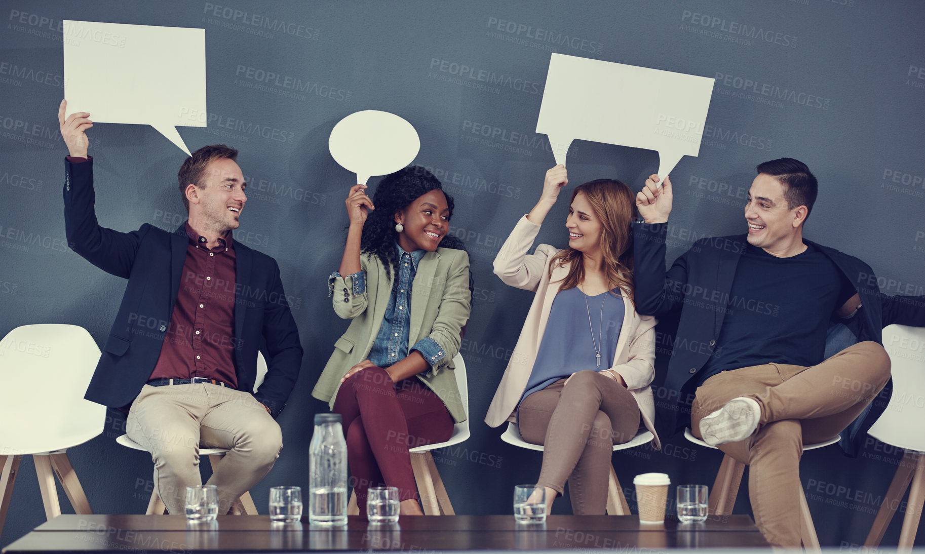 Buy stock photo Shot of a group of businesspeople holding up speech bubbles while waiting in line for an interview