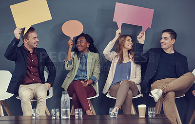 Buy stock photo Shot of a group of businesspeople holding up speech bubbles while waiting in line for an interview